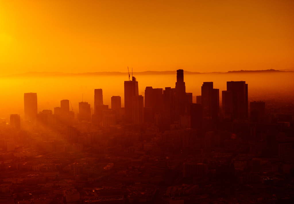 A city skyline is bathed in an orange sunset.
