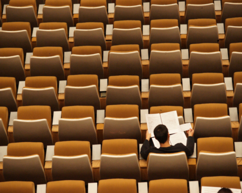 A university student reads his notes in an otherwise empty lecture hall.