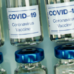 A photo of glass vials labeled "Covid-19 Vaccine"