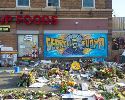 The George Floyd memorial at his place of death is strewn with flowers, notes, and a mural of his face and name.