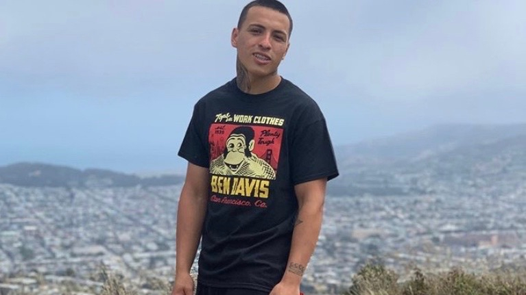 A photo of Sean Monterrosa, standing on a hill in front of a city.