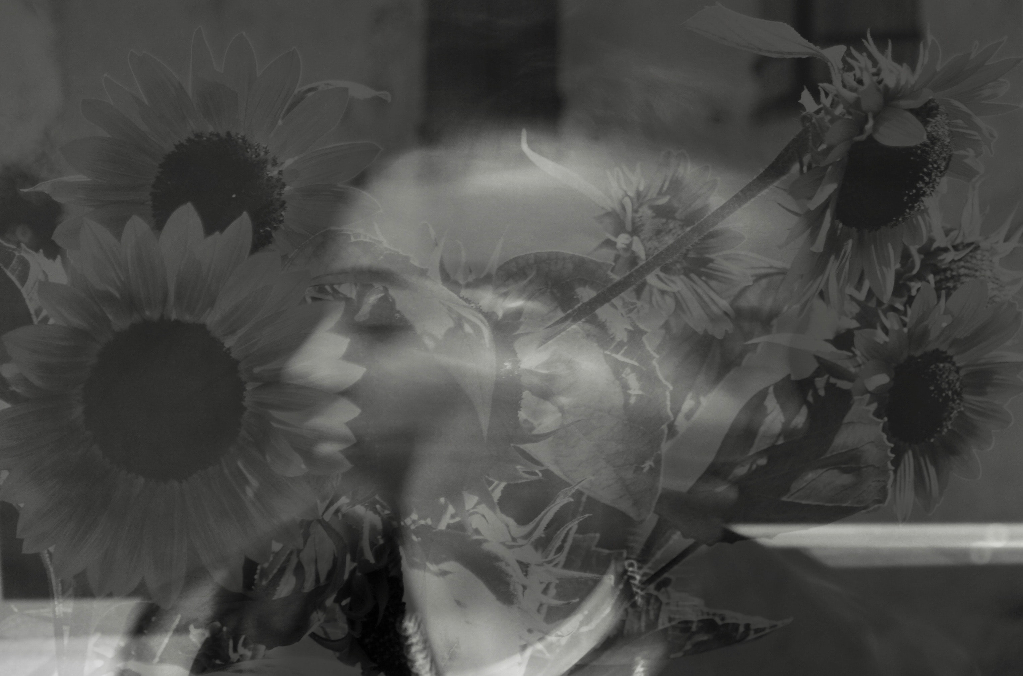 A black and white image of a woman's face superimposed with sunflowers.