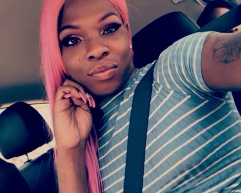 A photograph of Muhlaysia Booker, a Black woman with pink hair and a blue and white shirt in her car.