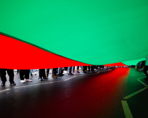 Under the flag of Afghanistan, the feet of a crowd.