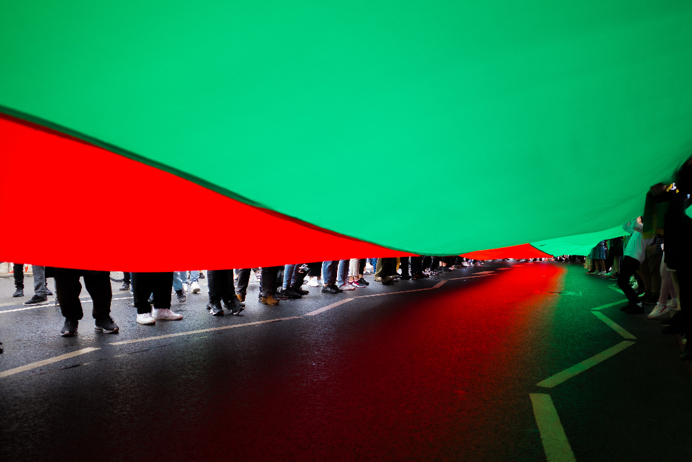 Under the flag of Afghanistan, the feet of a crowd.