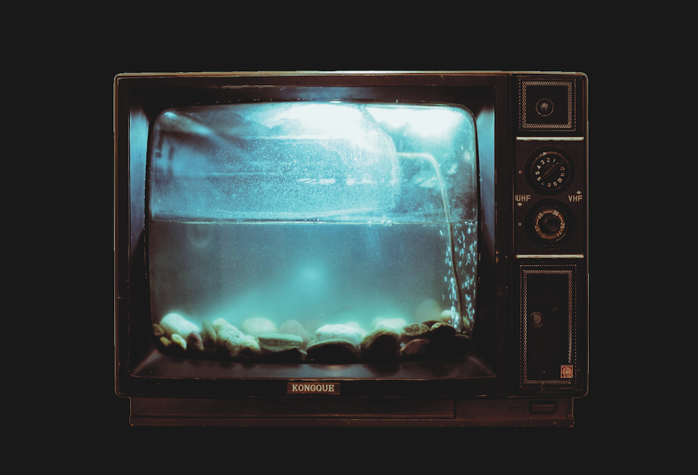 A photograph of a television set that has been turned into an aquarium full of water, and stones, with no life visible.